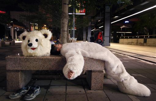 An environmentalist dressed as a polar bear rests after a candlelight vigil to raise awareness of climate change in Taipei