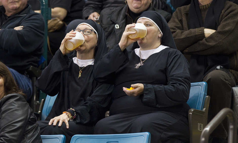 Two women wearing nun outfits drink beer at the 2014 Tim Hortons Brier curling championships in Kamloops