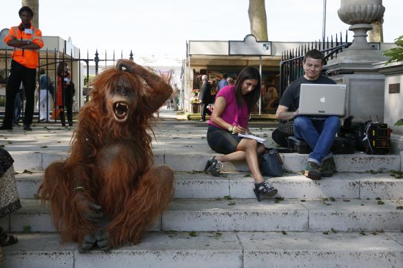 A man dressed as an orangutan sits next to members of the press during media day at the Chelsea Flower Show in London