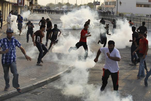 Anti-government protesters take cover from tear-gas fired by the police as they clash in the village of Sitra