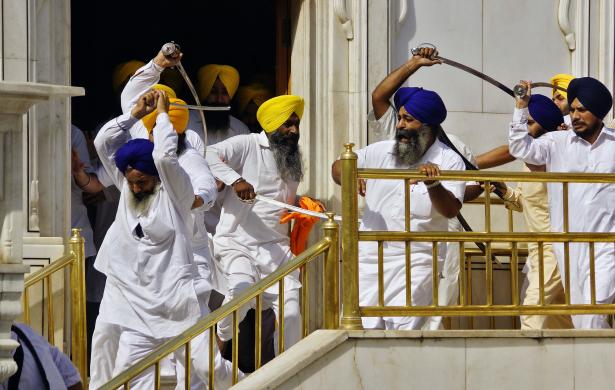 Sikhs wield swords during their clash inside the complex of the holy Sikh shrine, the Golden Temple, in Amritsar
