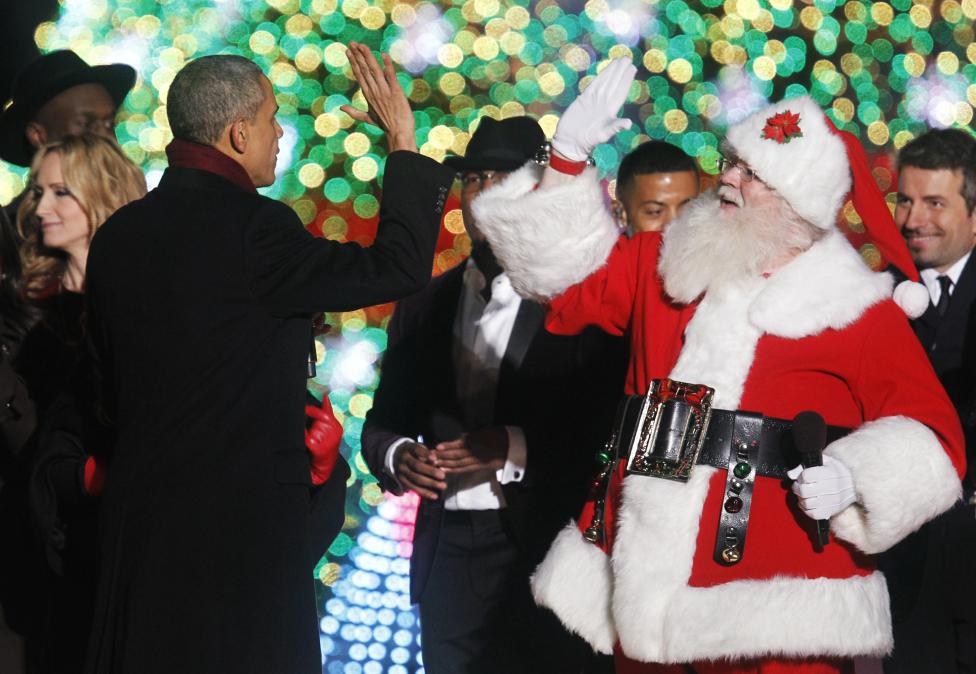 U.S. President Barack Obama gives a high five to a man dressed as Santa Claus during the 92nd annual National Christmas Tree Lighting on the Ellipse in Washington