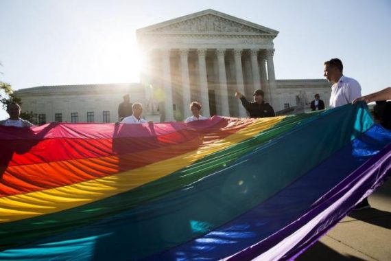Gay marriage supporters hold a gay rights flag in front of the U.S. Supreme Court before a hearing about gay marriage