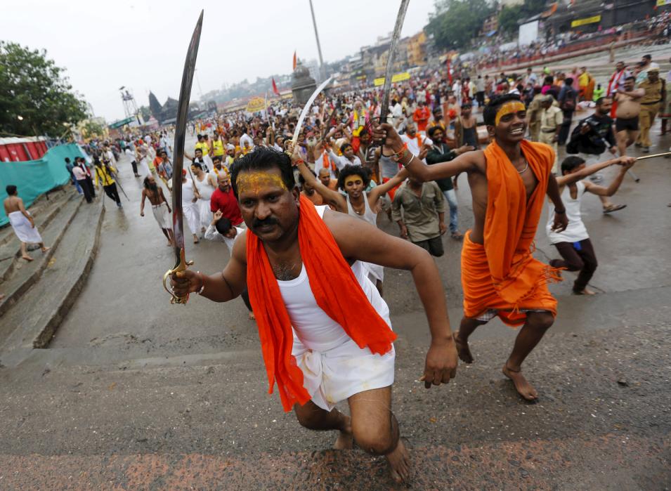 Sadhus or Hindu holy men hold swords as they run towards the banks of Godavari river to take a dip during the Kumbh Mela in Nashik