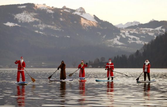 People dressed as Santa Claus pose on their stand-up paddles as they cross Lake Aegerisee near Oberaegeri, Switzerland December 5, 2015.  REUTERS/Arnd Wiegmann      TPX IMAGES OF THE DAY