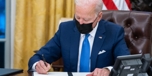 President Joe Biden signs executive orders on immigration Tuesday, Feb. 2, 2021, in the Oval Office of the White House.