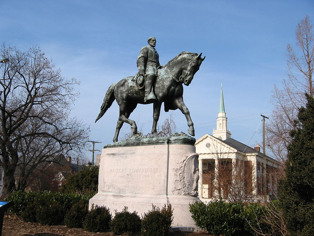 Portrait of a Robert E. Lee astride his horse, Traveller. Lee is bare-headed, wearing a military uniform, sitting very erect with his sword at his proper left side. His proper left hand is on the reins, and his proper right hand hangs down, holding his hat. The horse is in a walking pose with his proper left front hoof raised. On the front of the base is a relief depicting a fighting eagle with wings expanded, surrounded by clusters of oak leaves. On the back of the base is a relief of a garland.